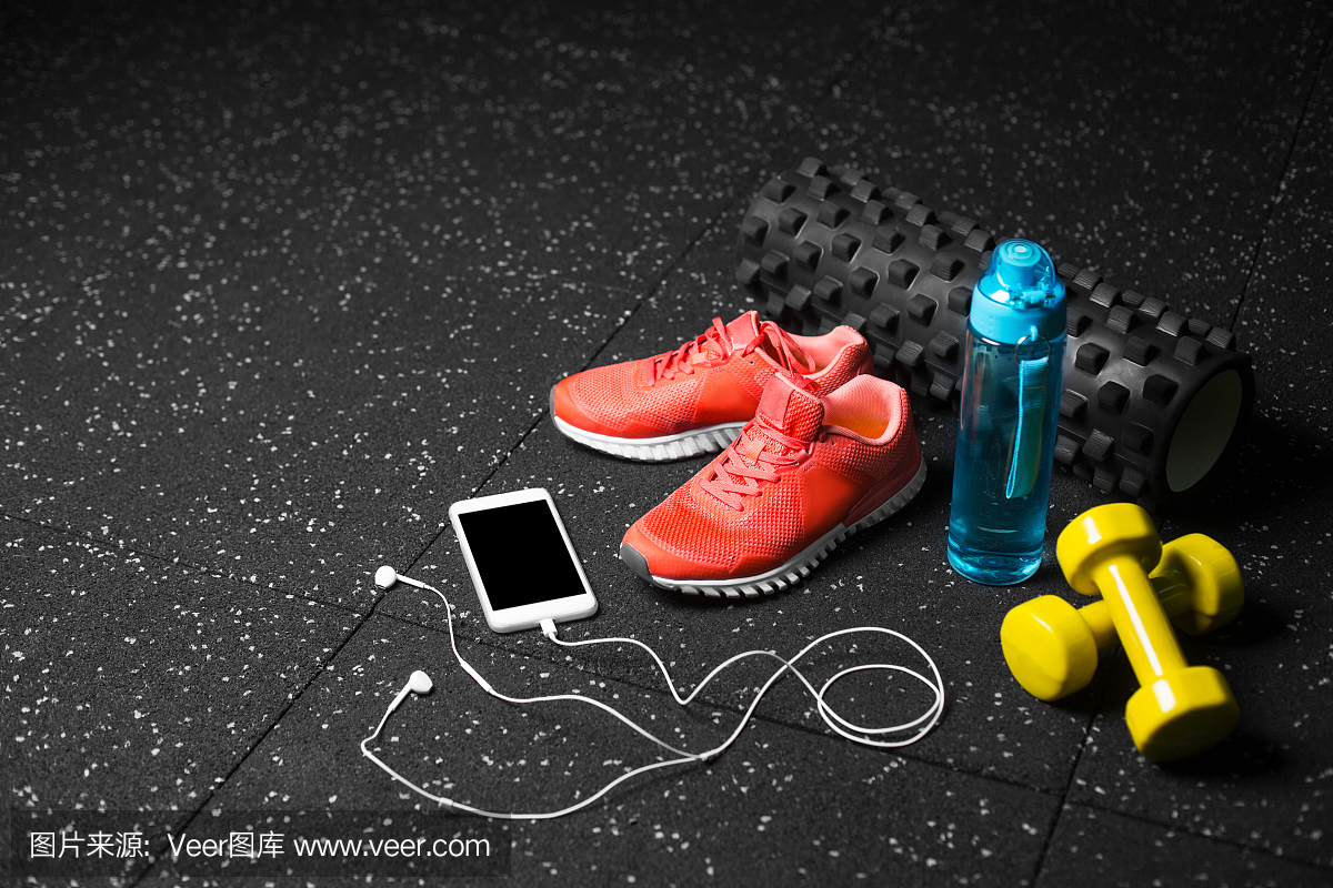 舒适的训练鞋,橡胶垫,哑铃,运动瓶和电话在黑点的背景。副本的空间。